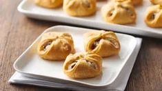 several small pastries sitting on top of a white plate next to a tray of cookies