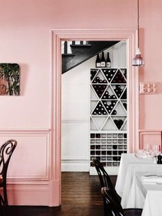 a dining room with pink walls and chairs