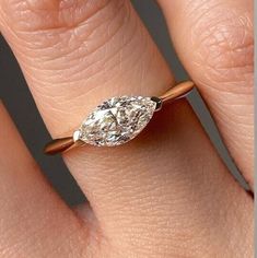 a woman's engagement ring with a pear shaped diamond in the center, on her finger