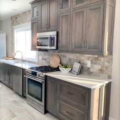 a kitchen with gray cabinets and white counter tops, stainless steel appliances and an oven