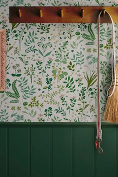 a broom and brush are hanging on the wall next to a coat rack with hooks