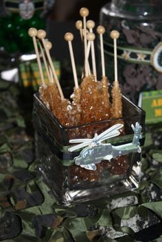 there are many candies in a glass container on the table with candy sticks sticking out of it