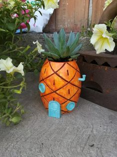 a pineapple shaped planter sitting on top of a cement slab next to flowers