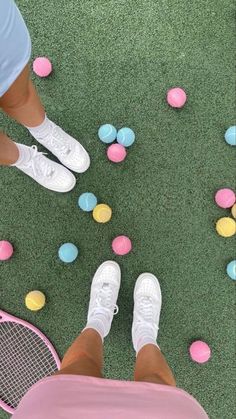 two people with tennis rackets and balls on the ground in front of their feet