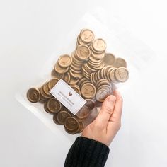 a person's hand holding a plastic bag filled with coins