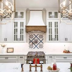 a kitchen with white cabinets and an island in front of the stove top, surrounded by hanging lights