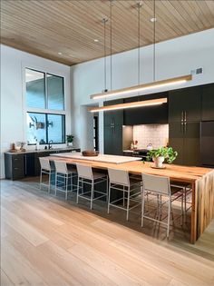 a large kitchen with wooden floors and white walls, along with an island table surrounded by chairs