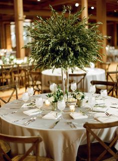 the table is set with white linens and greenery for an elegant centerpiece