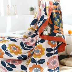 a woman standing on top of a bed covered in a colorful flowered bedspread