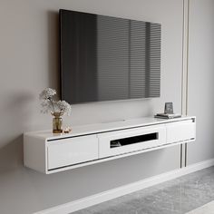 a white entertainment center with a large mirror on the wall and flowers in vases next to it