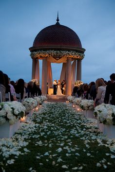 an outdoor ceremony with white flowers and greenery on the ground, surrounded by candles