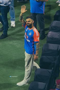 a man waves to the crowd as he stands in front of an audience at a sporting event