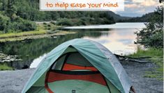 an orange and green tent sitting on top of a gravel road next to a lake