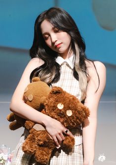 a woman holding two brown teddy bears in her hands