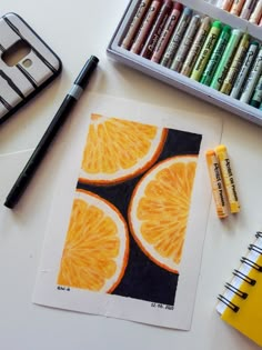 an orange cut in half next to some markers and crayons