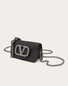 Valentino Garavani Locò micro bag in calfskin with chain and VLogo Signature element covered with Swarovski® crystals. Equipped with both a detachable sliding chain strap and a detachable handle, this accessory can be worn as a crossbody/shoulder bag or carried as a handbag. - Matching hardware - Magnetic closure - Removable leather handle - Shoulder strap with removable sliding chain - Nappa leather lining. Interior: one card slot Shoulder strap drop length: 55 cm / 21.6 in. - Handle drop lengt Luxury Leather Wallet On Chain For Parties, Luxury Chain Bag For Events, Silver Leather Wallet On Chain, Silver Leather Wallet On Chain For Evening, Rectangular Wallet On Chain For Evening, Rectangular Evening Wallet On Chain, Luxury Evening Bag With Chain Strap, Luxury Wallet On Chain For Party, Luxury Party Wallet On Chain