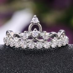 a tiara is shown on top of a black surface with purple flowers in the background