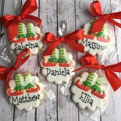 decorated cookies in the shape of christmas stockings with name tags on them and red bows