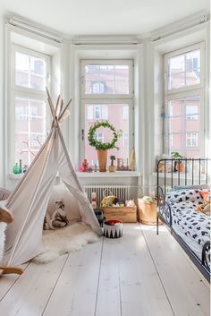 a bedroom with a teepee tent in the corner and other items on the floor