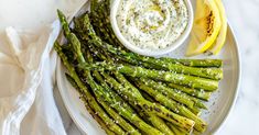 asparagus on a plate with lemon wedges and dip