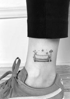 a woman's foot with a small tattoo on the side of her leg and a bathtub