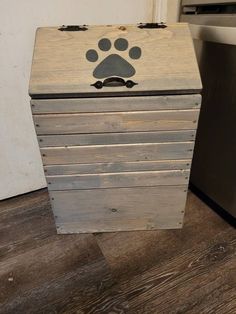 This is a wooden dog food storage container binIt measures approximately 26 inches tall18 inches wide and 10 inches deepthis bin will easily hold 30 pounds of dry dog foodInside of this bin is not stained to keep food safe for your petThis wood container has a paw print shape painted black on the lid (classic grey no-bone)with a black hammered handle attachedThis bin also has one magnetic closure to help keep the lid in a closed positionA pegboard back is nailed onto this bin to Wooden Dog Food Storage Diy, Wood Dog Food Storage, Diy Dog Food Storage Container, Diy Pet Food Storage, Dog Food Container Ideas, Dog Food Cabinet, Dog Food Storage Ideas, Large Dog Food Storage, Dog Food Storage Diy