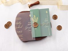 wedding stationery with coins and ribbon on table next to white background, including wax stamp