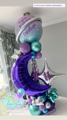 a birthday decoration with balloons, stars and moon in the shape of a crescent on top of a table