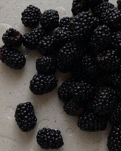 some blackberries are laying on a white surface