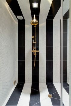 a black and white striped shower in a bathroom with gold faucet on the wall