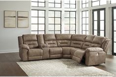 a large sectional couch with recliners in front of windows and a rug on the floor