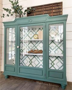 a green china cabinet with glass doors and shelves