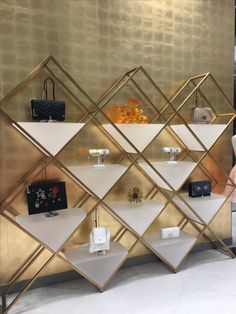 a gold and white display case with purses on it in front of a wall