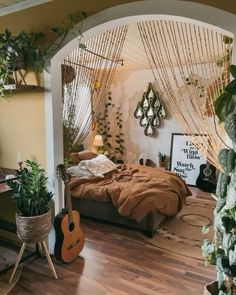 a bed room with a guitar on the floor and plants hanging from the wall behind it