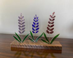 three metal flowers sitting on top of a wooden table