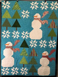 a quilted snowman and trees on a blue background