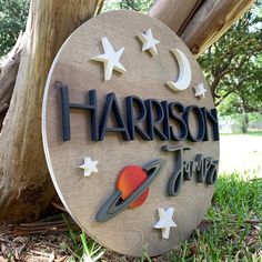 a wooden sign that says harrison with stars and the moon on it in front of a tree