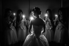 a woman holding two candles in front of her face while standing next to other women