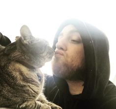 a man in a hoodie kissing a cat