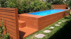 an above ground pool surrounded by wooden fence and grass in the back yard, with steps leading up to it