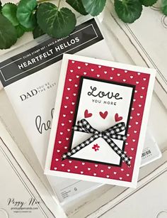 two cards with hearts on them sitting next to each other and some green leaves in the background