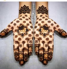 two hands with hendi designs on them, one is painted brown and the other is white