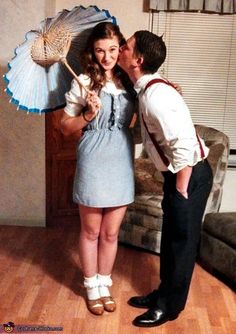 a man kissing a woman with an umbrella in front of her on a wooden floor