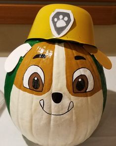 a close up of a pumpkin with a dog face on it's head and a baseball cap on top