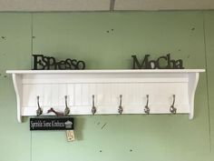 there is a white shelf with hooks on it and some letters hanging from the wall