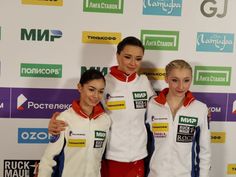 three women standing next to each other in front of a wall