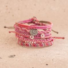 the pink bracelets are stacked on top of each other with silver beads and charms