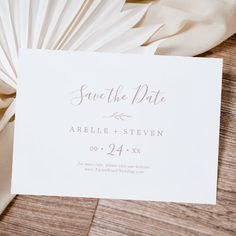 a close up of a wedding card on top of a wooden table with white cloth