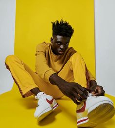 a man with dreadlocks sitting on a yellow chair and holding his foot up