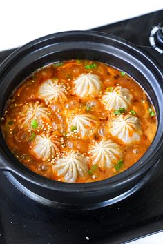 a black crock pot filled with soup and dumplings on top of a stove